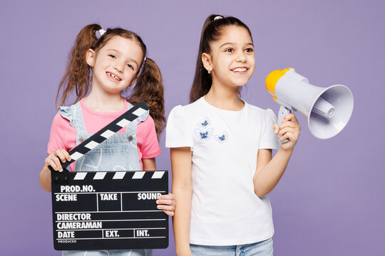 Little two friends kids children girls 9-10 year old wear casual clothes together hold classic black film making clapperboard scream in megaphone isolated on plain purple background Lifestyle concept