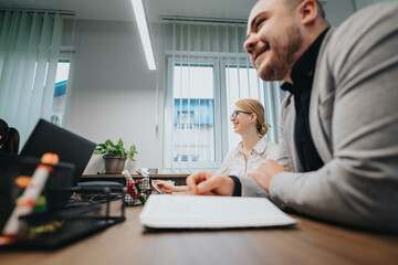 Business colleagues laughing together while working in a contemporary office space, creating a collaborative and enjoyable meeting environment