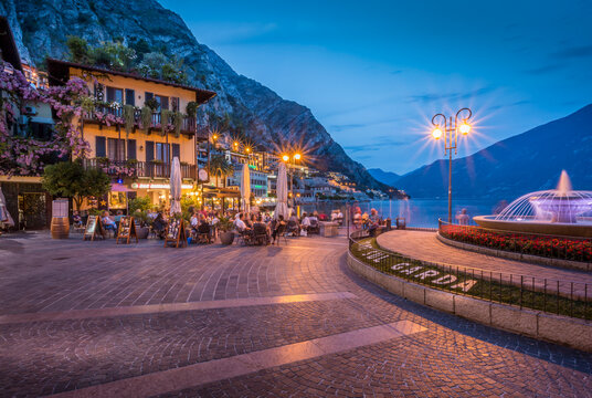 View of illuminated promenade at the port of Limone at dusk, Lake Garda, Lombardy, Italian Lakes, Italy