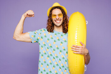 Young man wear blue beach t-shirt yellow hat sunglasses rest near hotel pool hold rubber ring...