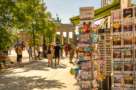 View of Brandenburg Gate, postcards and visitors in Pariser Platz on sunny day, Mitte, Berlin, Germany
