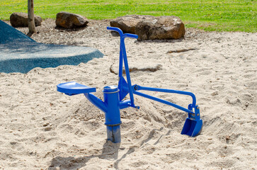 Metal digger play equipment in a sandy playground in Australia, designed for children to simulate digging and construction activities.Outdoor play equipment promotes physical activity in a public park