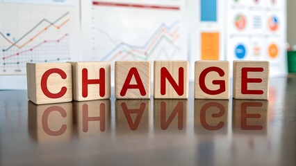 Wooden blocks spell out change symbolizing transformation and progress with financial charts in the background suggesting business strategy