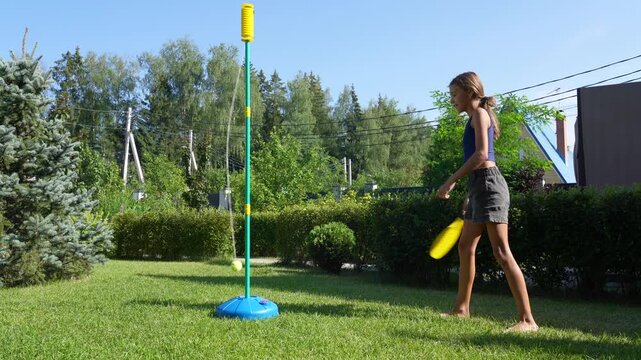 A girl plays tetherball in her sunny backyard