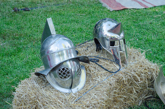 Two different gladiator helmets on display at a Roman camp.