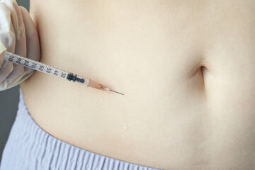 Insulin injection administered on bare stomach of a caucasian adult.