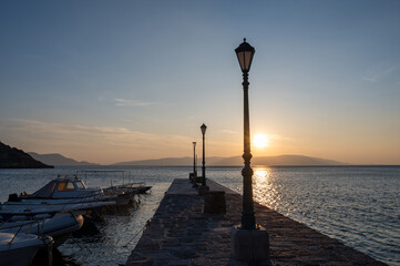 Lanterns on a pier with boats, by the sea at sunset