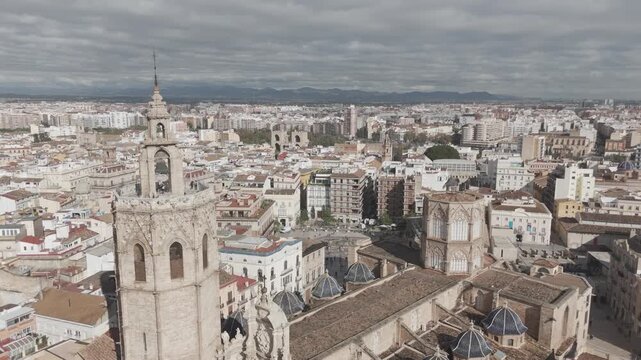 Dron ascendiendo con vista picada de la Torre del Miguelete y Plaza de la Reina en Valencia con gente en la torre