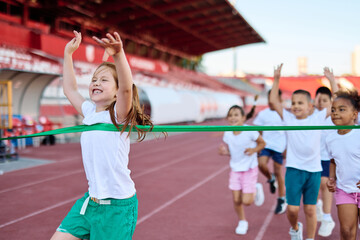 Young children having athletic exercise class running on the track, healthy lifestyle and children sport education concepts, finish line winner celebration, victory and success