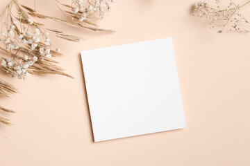 Blank square card mock up on soft pastel background surrounded by dried flowers, creating a serene and elegant atmosphere for design purposes and creative projects