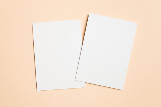 Two blank white sheets of paper on beige background, copy space for design purposes, ideal for invitation mockup presentations and creative projects