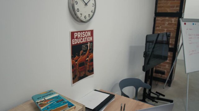 Panning no people shot of classroom in prison, with bright motivational posters on walls, laptops on desks, whiteboard and screen with sample of computer code, ready for programming lesson for inmates - Powered by Adobe