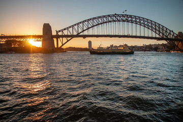 Sydney Harbour Bridge at sunset with boats on the water and city skyline in background