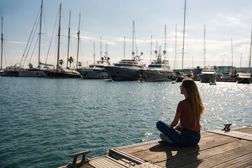 Fototapeta premium Pretty young lady sitting on a pier in a yacht club, Valencia, Spain
