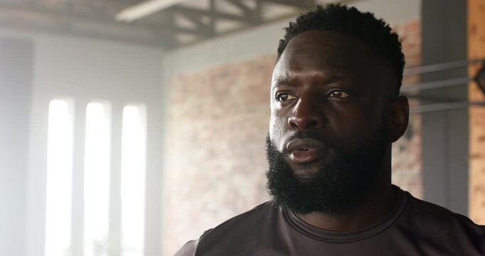 After completing training set, African American man catching breath in front of pull-up rig