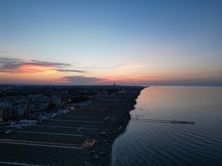 Coastal Sunset Panorama: A breathtaking aerial view of a serene coastline at dusk, where the sky is...