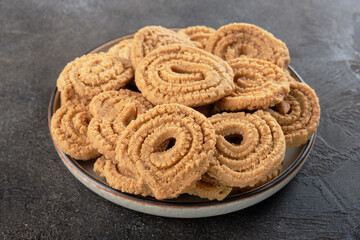 Indian fried snack murukku or chakali on a dark bcakground. Traditional Diwali food. Indian cuisine