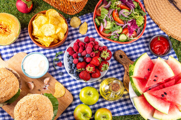 Tasty summer barbecue table with hamburgers, salads, fruits and snacks