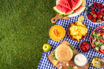 Tasty summer barbecue table with hamburgers, salads, fruits and snacks