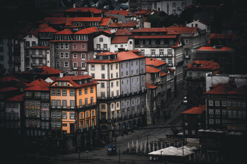 Porto, Portugal - 17 June 2022: View of terracotta rooftops cascading across aged buildings, a warm, inviting contrast to the cool, shadowed streets below.