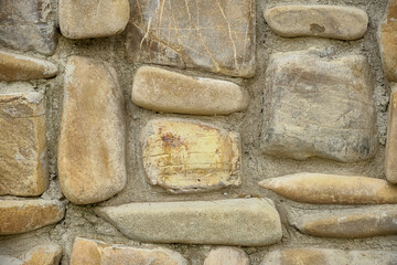 Natural textured stone wall with irregular shapes and earthy tones, perfect for backgrounds and architectural details.