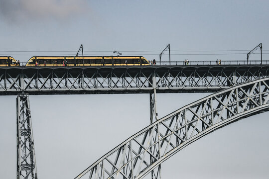 Porto, Portugal - 17 June 2022: View of the Dom Lu&Atilde;&shy;s I Bridge, its metallic arches reaching across the sky as a train glides over, a marvel of engineering and transport..