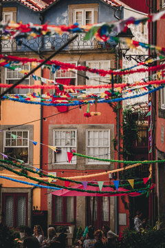 Porto, Portugal - 17 June 2022: View of vibrant buildings adorned with colorful streamers, casting shadows on the animated street below.