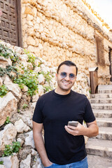 Obraz premium Happy man holding smartphone, traveling in old town of Guadalest in Spain