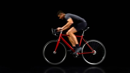 Fototapeta premium A blurred shot of a man riding a red bicycle against a black background