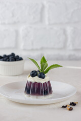 Jelly with blueberries, mint, anchan tea and cream in a plate. Homemade dessert, sugar and lactose free. Vertical orientation.