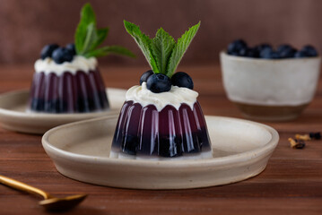 Jelly with fresh blueberries, mint, anchan tea and cream with agar agar on a wooden table. Summer dessert, gelatin free.