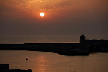 Evening colorful landscape with view of coastline of Vila du Conde, Portugal. Red sun in fluffy clouds over the ocean