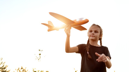 Child play toy airplane. Girl aviator wants to become pilot, astronaut. Happy kid runs with toy airplane on field, sunset. Teenager dreams of flying, becoming pilot