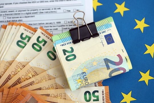 European euro currency money notes bunch on tax form and European union blue flag close up