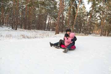Father and daughter having fun with snow tube in the forest