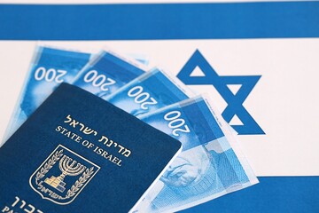 Israel New Shekels banknotes and passport on flag. The current Israel money bills and pass