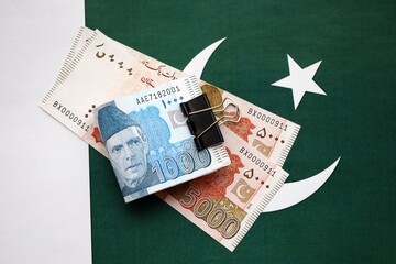 Pakistan rupees banknotes on Pakistani flag. The current Pakistan money bills
