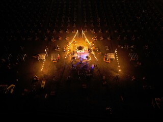 Illuminated Stage in Darkness: An elevated, wide-angle view of an elaborate outdoor stage setup, awash in warm amber light, provides an atmospheric backdrop to an unseen performance. Rimini, Italy