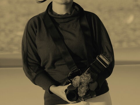 Beautiful woman under 35 years old standing on the sea and beach with a photo camera in Ruach in the hands of Rosa in black and blue shorts