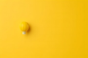 single bright yellow light bulb on a plain yellow background representing a creative idea