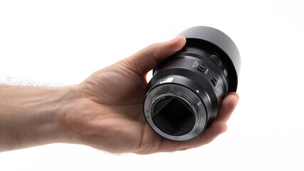 Hand holding a black camera lens with focus ring