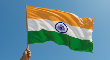 Hand holding the vibrant Indian national flag waving proudly against a clear blue sky, symbolizing patriotism.