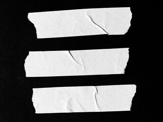 A set of blank white adhesive paper tape in rectangular shape isolated on black background with clipping path. The white paper looks vintage with wavy paper texture and wavy edges.