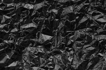 Shiny black foil texture background, pattern of wrapping paper with crumpled and wavy.