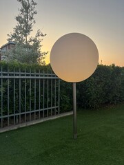 Outdoor spherical lamp at sunset in modern garden setting