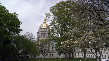 Fototapeta premium Visit the West Virginia State Capitol in Charleston, showcasing stunning architecture and surrounded by blossoming trees, making it a popular tourist destination.