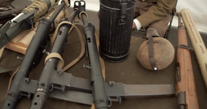 An educational display of WWII infantry armaments. Reenactors in the background present historic British and German weapons to visitors.
