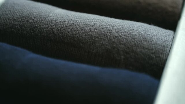 Rolled socks neatly arranged in box, showcasing variety colors from dark blue, gray to brown, suggesting well organized wardrobe or diverse sock collection. Collection rolled socks in different colors