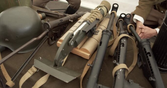 A display of historic WWII armaments. The collection includes British PIAT anti-tank weapons and Sten guns, alongside a German Stahlhelm helmet. Military history exhibit.