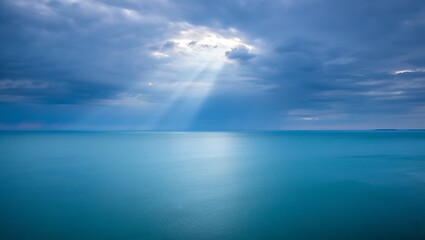 Fototapeta premium Photo of sun rays pierce through the clouds, illuminating the tranquil sea, creating a breathtaking scene of natures beauty with a serene and calming atmosphere